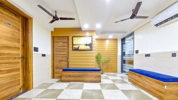 A hotel lobby with wooden benches, a ceiling fan, and a wall-mounted air conditioner. - Fabhotel Elite (Dehradun)