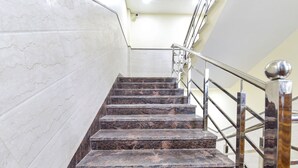 A marble staircase with metal railings and a handrail, leading to an upper floor. - Fabhotel Elite (Dehradun)