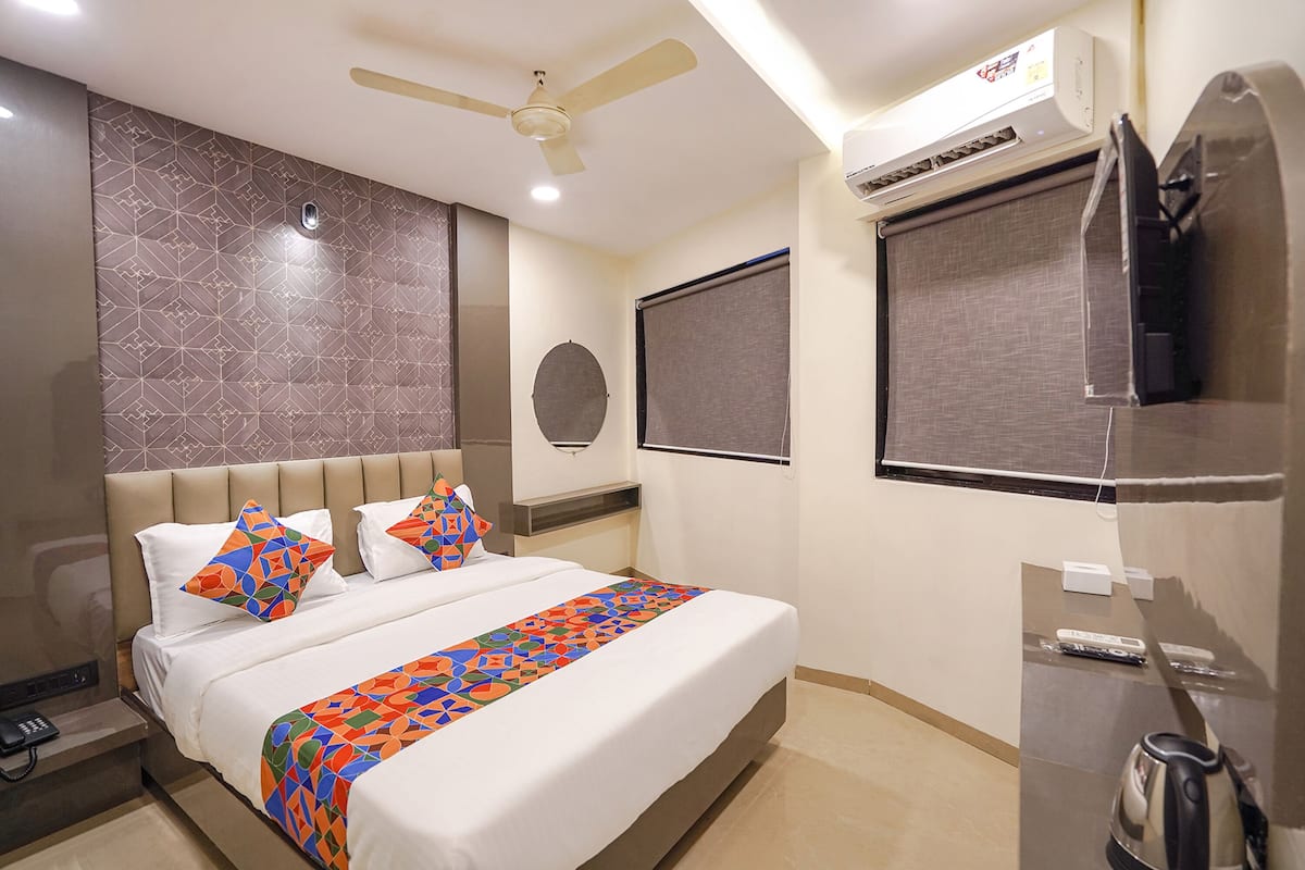 Une chambre d’hôtel équipée d’un lit, d’un ventilateur de plafond, d’un climatiseur, d’une télévision et d’une bouilloire.