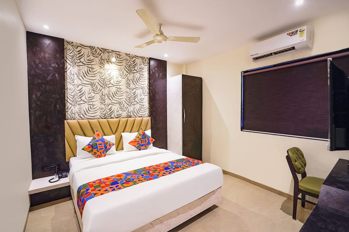 Une chambre d’hôtel équipée d’un lit, d’un bureau, d’une chaise, d’un ventilateur de plafond et d’un appareil de climatisation.