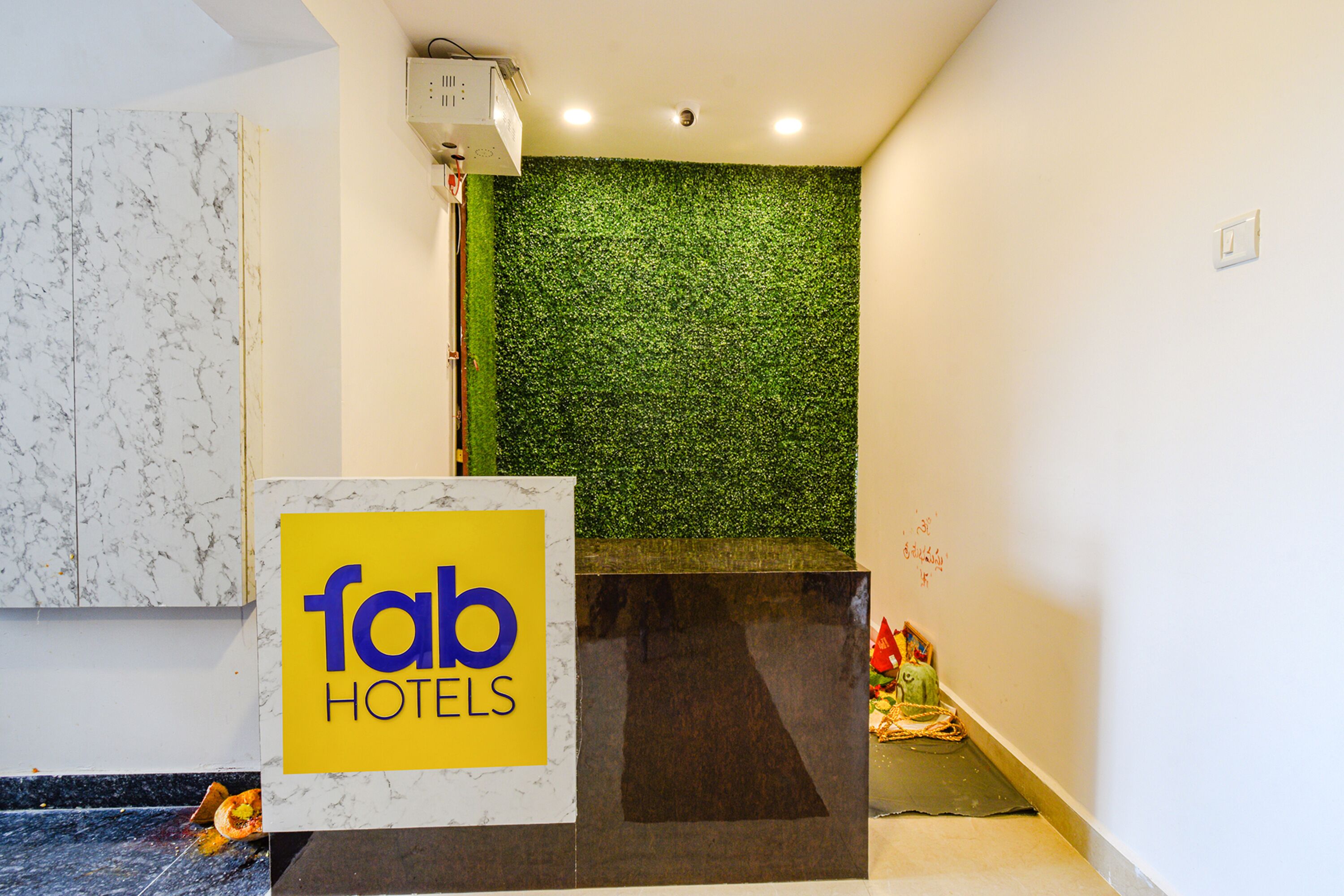 A reception area with a marble wall, a green wall with foliage, and a sign for 'fab hotels'.