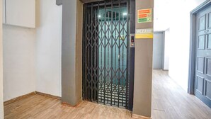 An elevator with a metal gate, a number 2 sign, and a 'Please wait' sign.