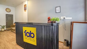 A reception desk with a 'fab hotels' sign, a clock, and a framed certificate on the wall.