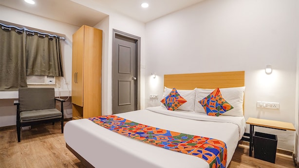 A hotel room with a bed, a chair, a desk, and a wardrobe.