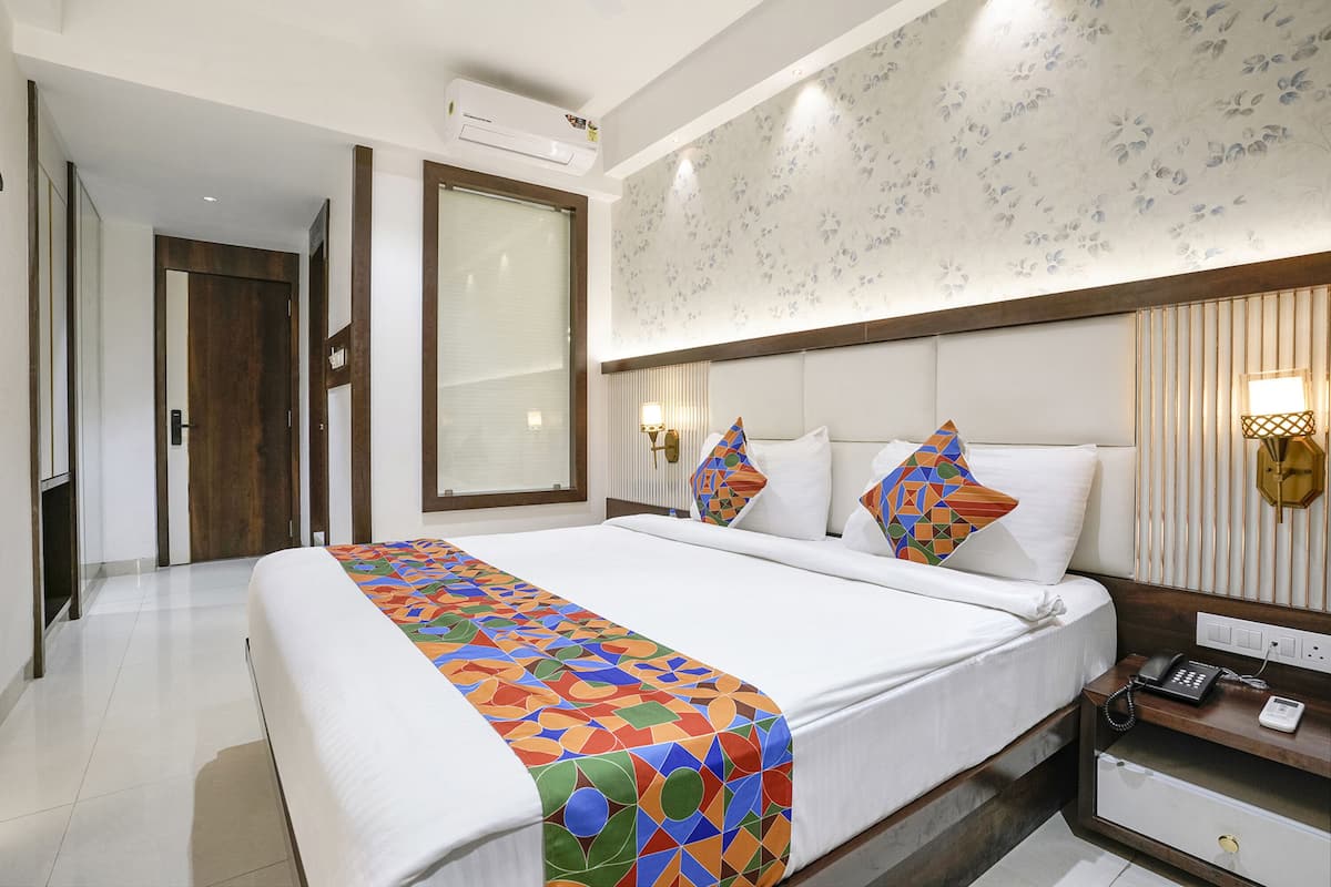 Une chambre d’hôtel avec un grand lit, une table de chevet avec un téléphone et une lampe fixée au mur.