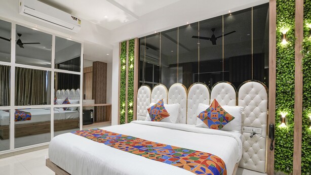 A modern bedroom with a large bed, a built-in wardrobe, and a large window with a view. - Fabhotel Melody Boutique (Thane)