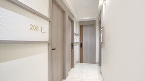 A hallway with a number '206' on the wall, wooden doors, and a marble floor. - Fabhotel Melody Boutique (Thane)