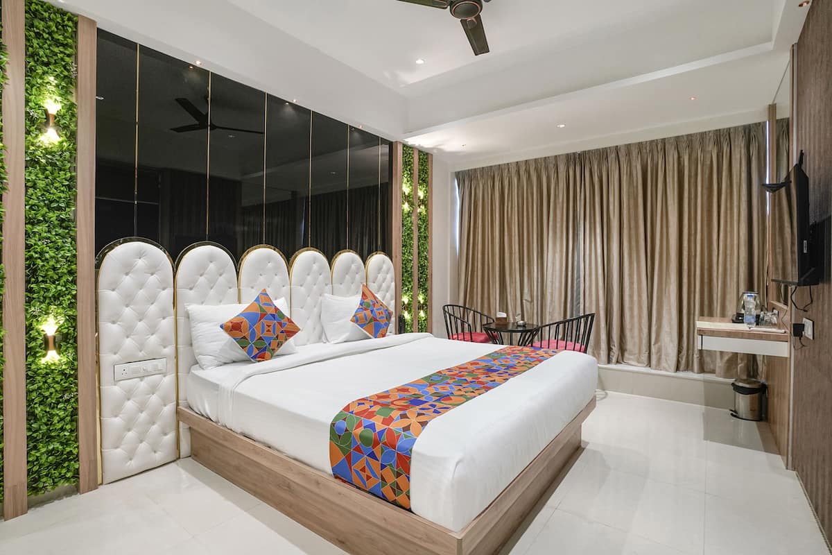 Une chambre moderne avec un grand lit, un ventilateur de plafond, une télévision et une petite table avec une chaise.