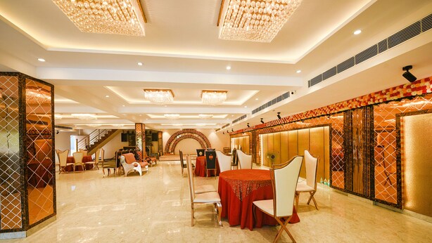 A spacious hotel lobby with a marble floor, a central round table with chairs, and a staircase in the background. - FabHotel Arjun Luxury Banquets and Rooms (New Delhi)
