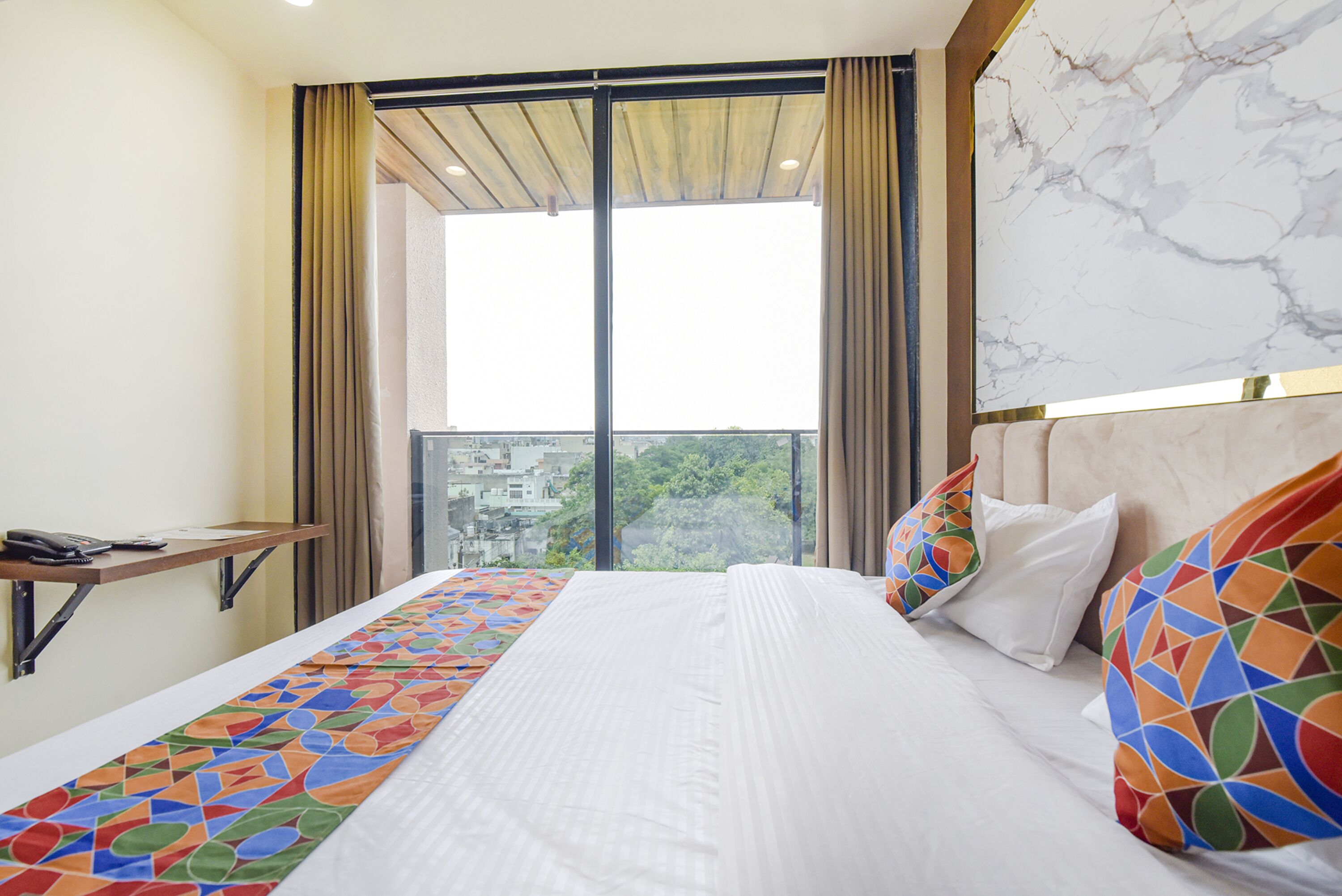 Una habitación de hotel con una cama grande, un escritorio y vistas de la ciudad a través de amplios ventanales.