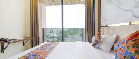 Una habitación de hotel con una cama grande, un escritorio y vistas de la ciudad a través de amplios ventanales.