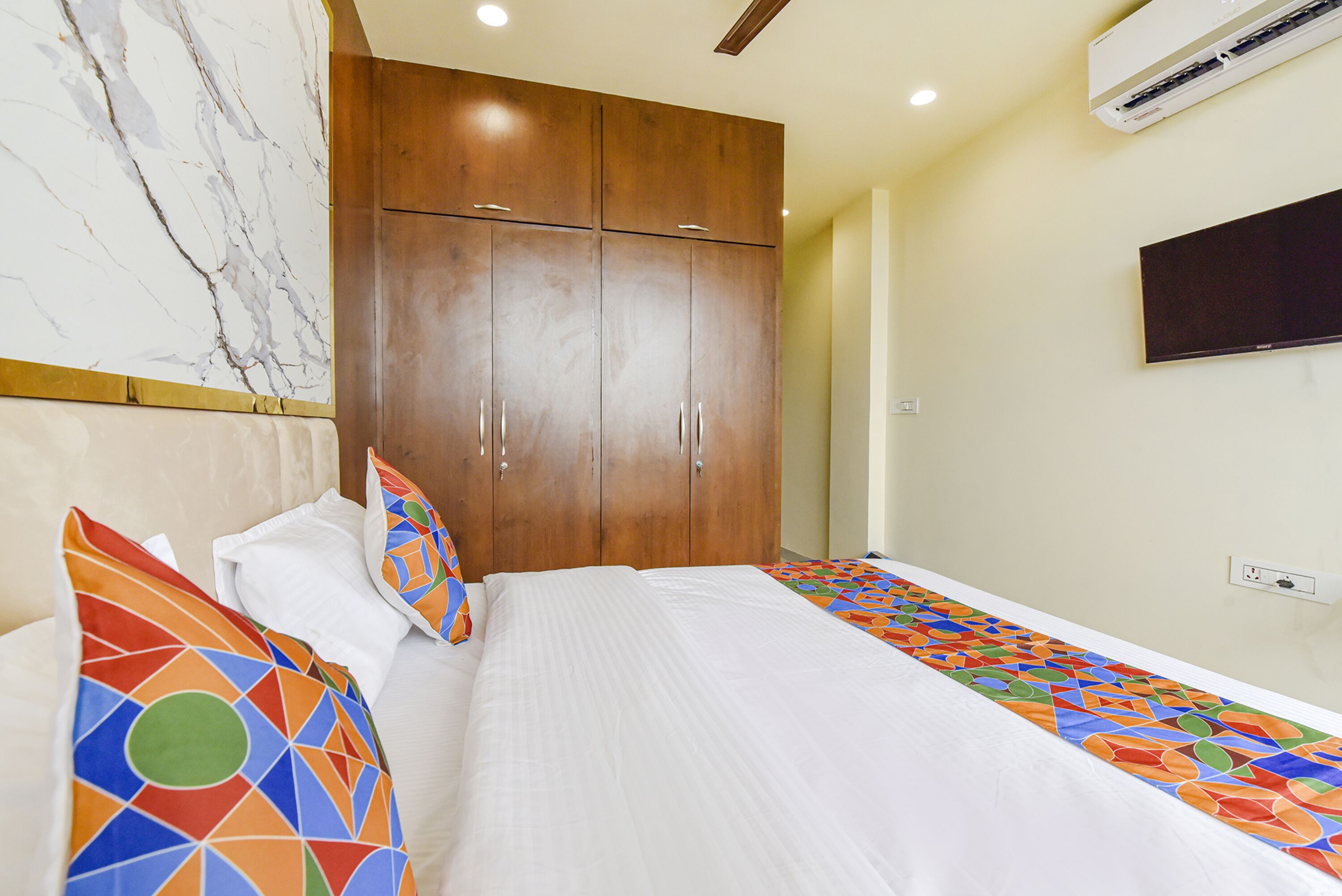 A hotel room with a bed, a wardrobe, and a television on the wall.