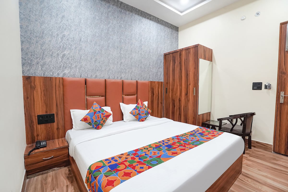A hotel room with a large bed, a wooden wardrobe, a bedside table, and a nightstand.