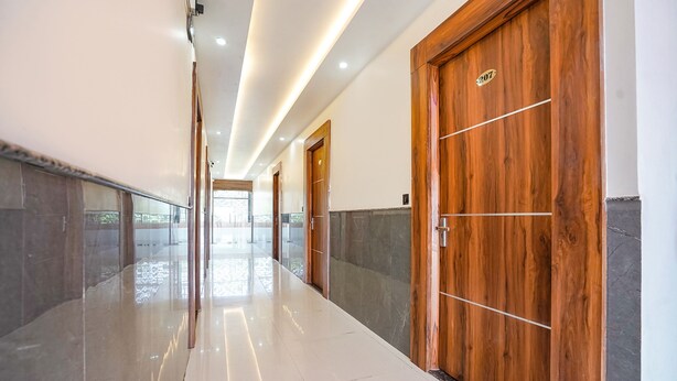A hallway with polished floors, wooden doors, and a stone wall. - Fabhotel The Vrindavan Inn (Mathura)