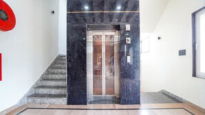 A modern elevator with a glass door, a marble staircase, and a clean, minimalist interior. - Fabhotel The Vrindavan Inn (Mathura)