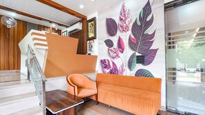 A modern interior with a staircase, a sofa, and a wall with leaf patterns. - Fabhotel The Vrindavan Inn (Mathura)