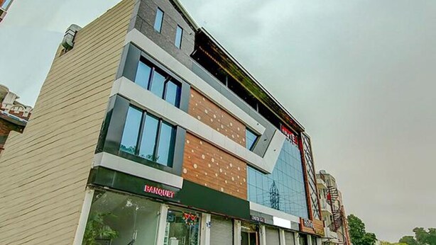 A multi-story building with a modern architectural design, featuring a mix of glass and wood paneling on the facade. - Fabhotel Aditya And Kings (Panchkula)