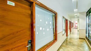 A hallway with wooden doors and frosted glass panels, leading to rooms. - Fabhotel Aditya And Kings (Panchkula)