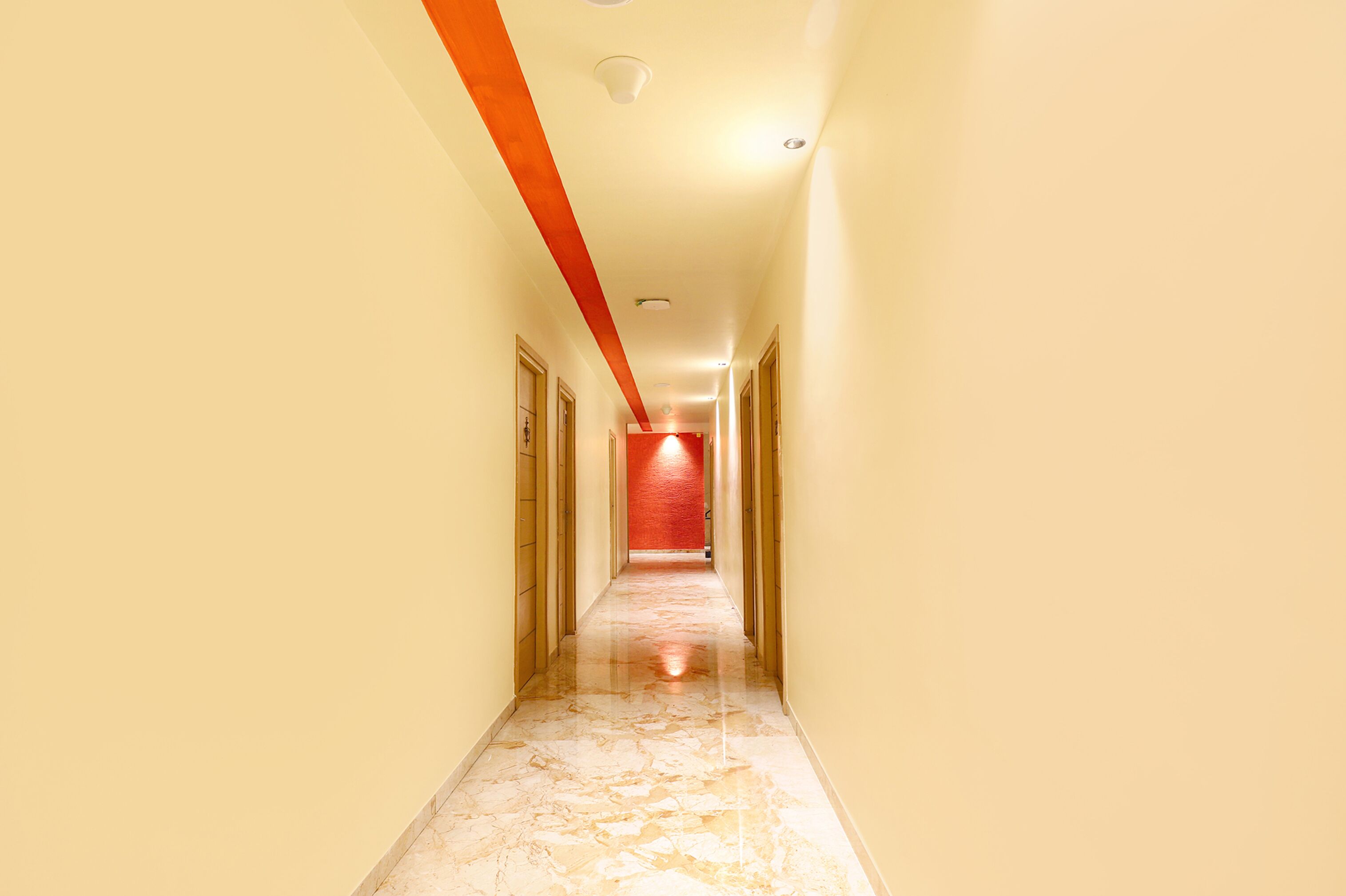 Un long couloir étroit, doté d’un sol en marbre et d’un mur d’accent rouge au fond.