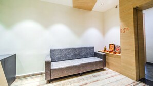 Una moderna zona de recepción con un sofá gris, un mostrador de madera y un suelo de mármol.