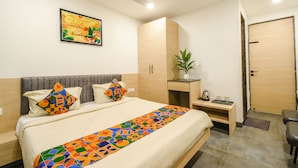 Un dormitorio ordenado con cama, mesitas de noche, armario, ventilador de techo y un cuadro en la pared.