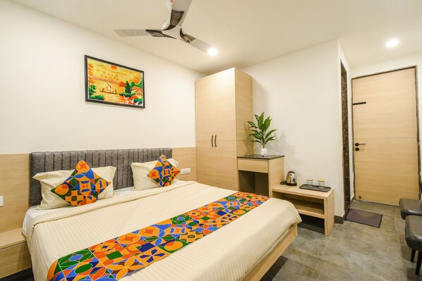 A neatly arranged bedroom with a bed, bedside tables, a wardrobe, a ceiling fan, and a painting on the wall.