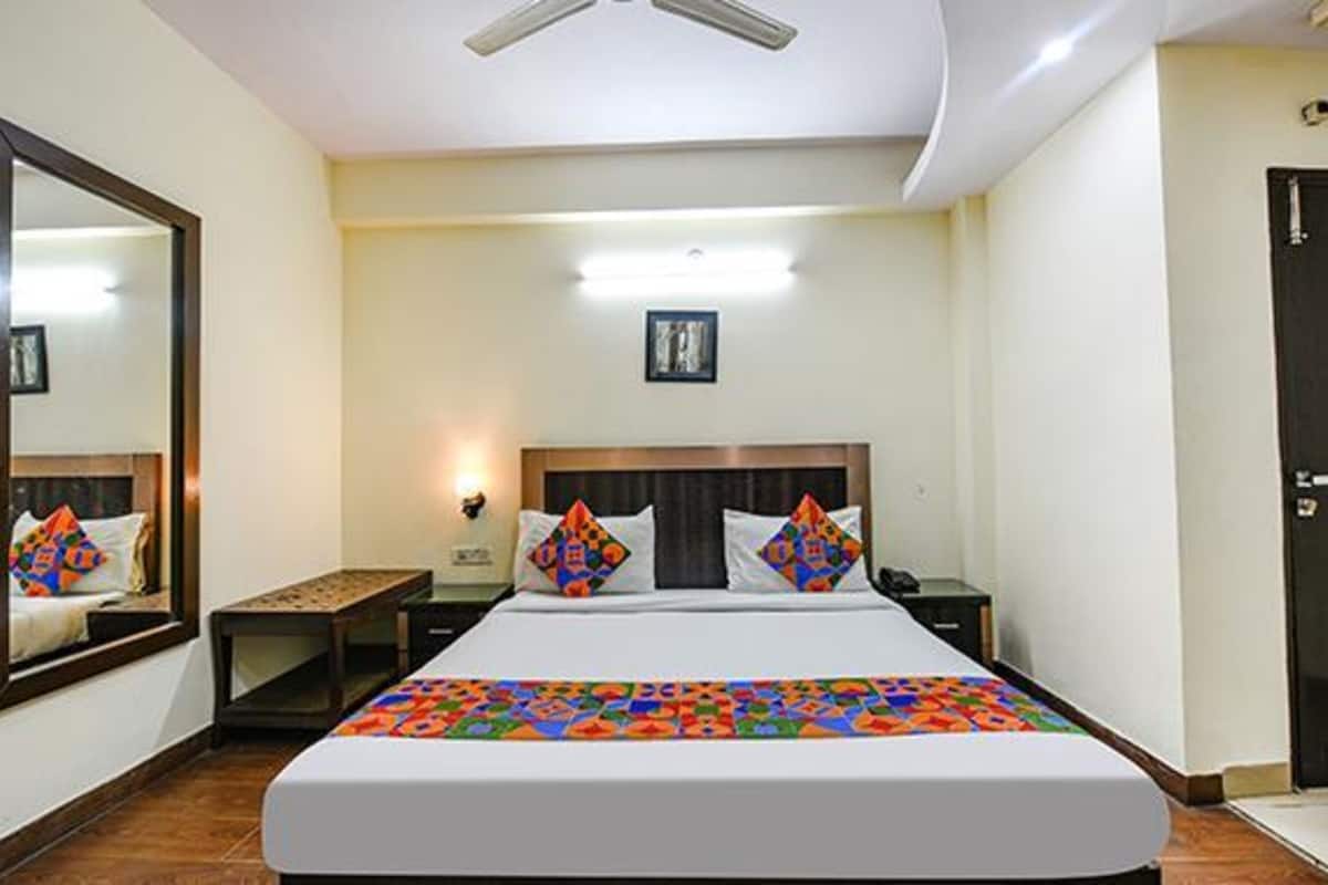 Habitación de hotel con una cama grande, una mesita de noche, un escritorio, una silla, una puerta y un ventilador de techo.