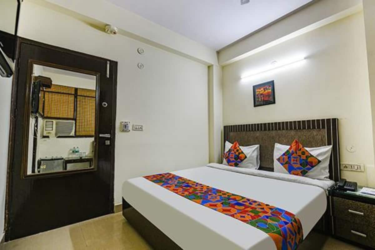 Habitación de hotel con cama, mesita de noche, escritorio y baño visible a través de una puerta abierta.