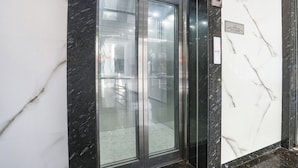 Ein moderner Aufzug mit Glastüren, einer Marmorwand und einem Schild, das die 2. Etage angibt.