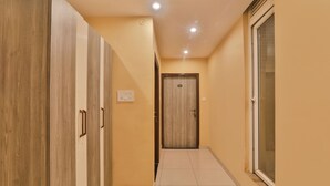 A hallway with wooden cabinets, a door with a number, and a window. - Fabhotel Ls Grand (Varanasi)