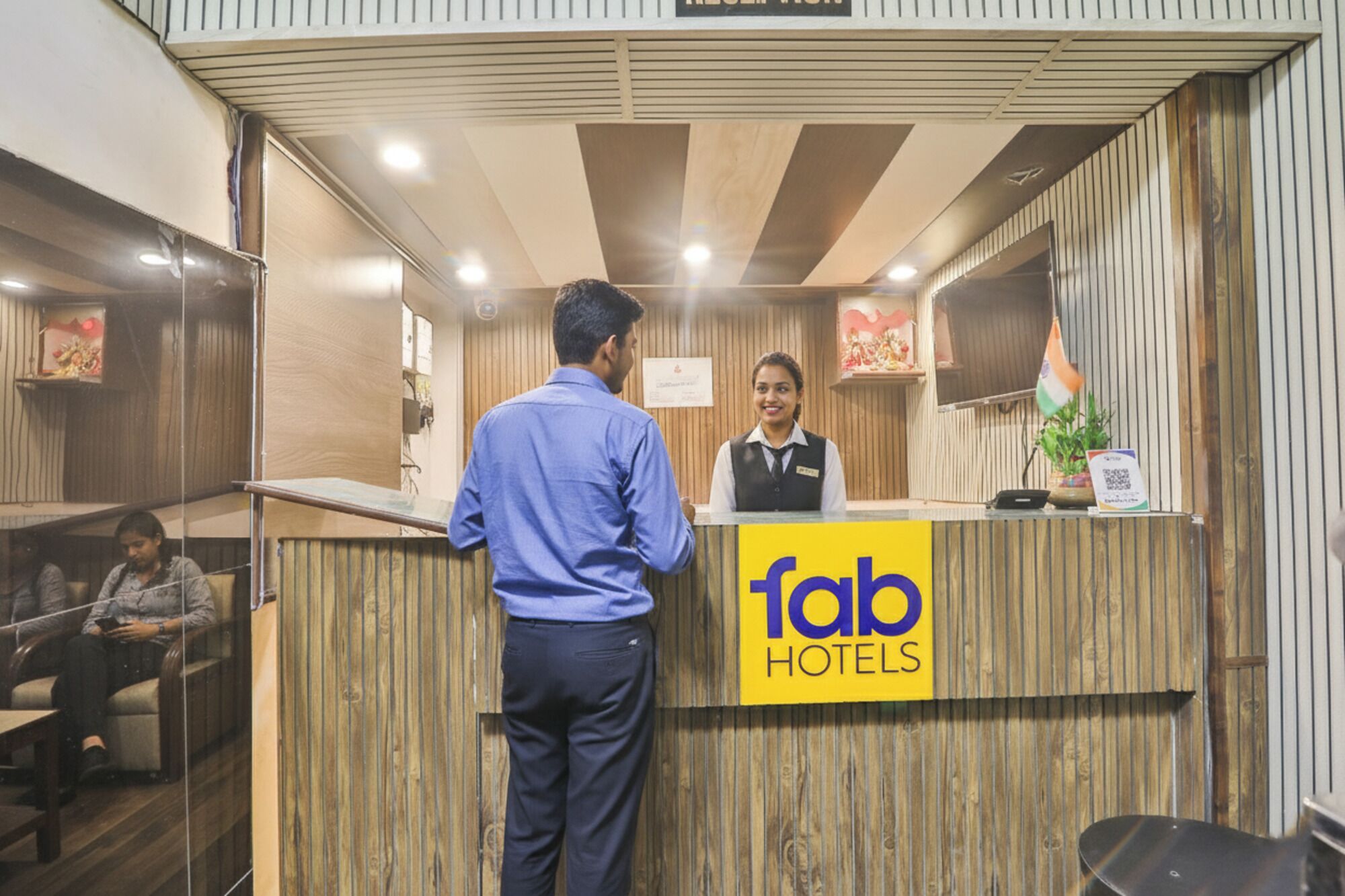 En receptionsdisk med træfinish, et skilt med teksten 'fab hotels' og et flag.