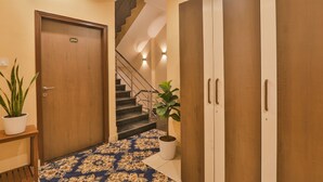 A hallway with a wooden door, a staircase, and a potted plant. - Fabhotel Ls Grand (Varanasi)