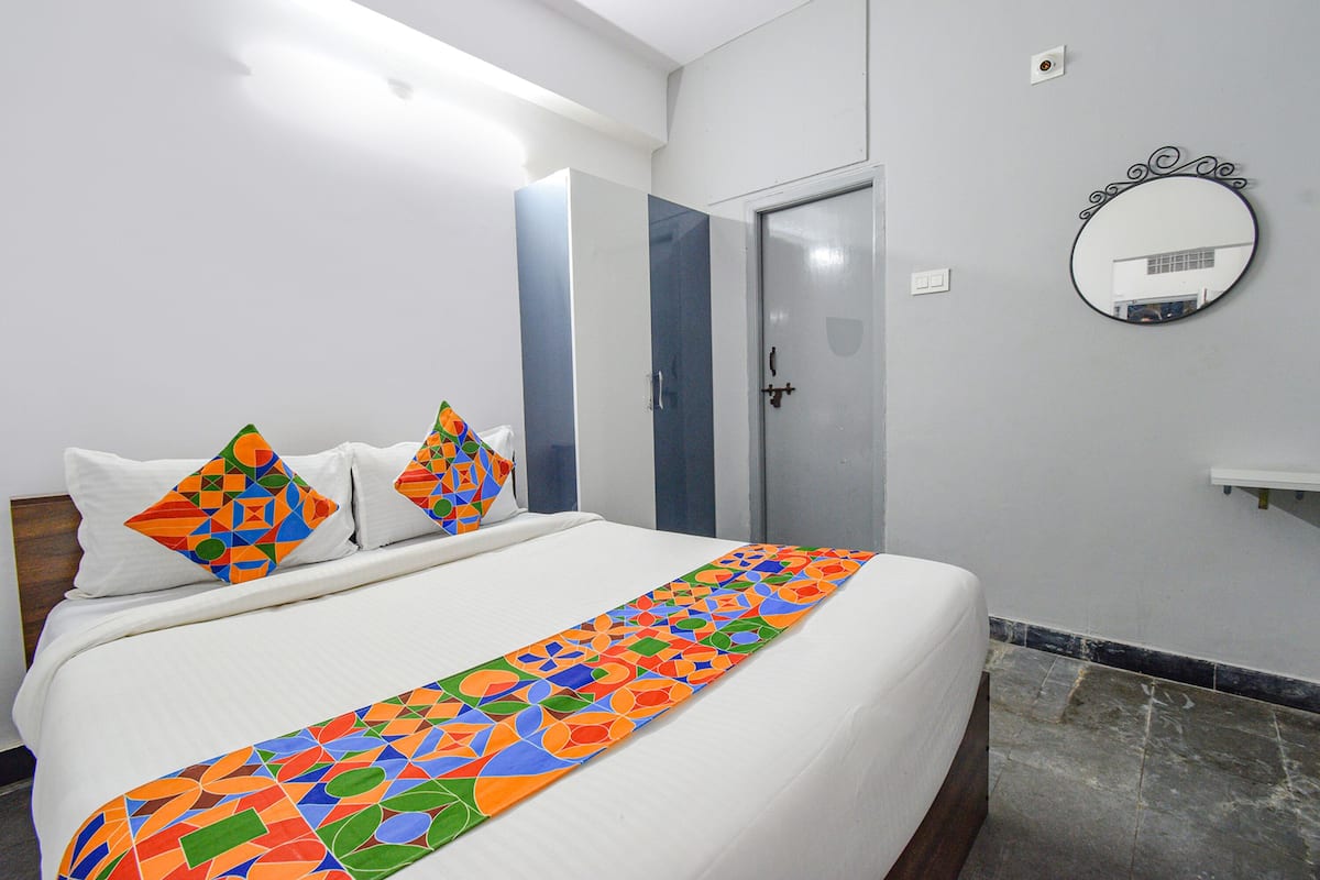 Une chambre d’hôtel avec un lit, un miroir et une porte.