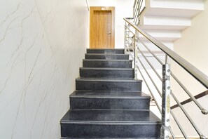 A staircase with black steps and a metal railing, leading to a wooden door. - FabHotel Somnath - Ujjain Railway Station (Ujjain)