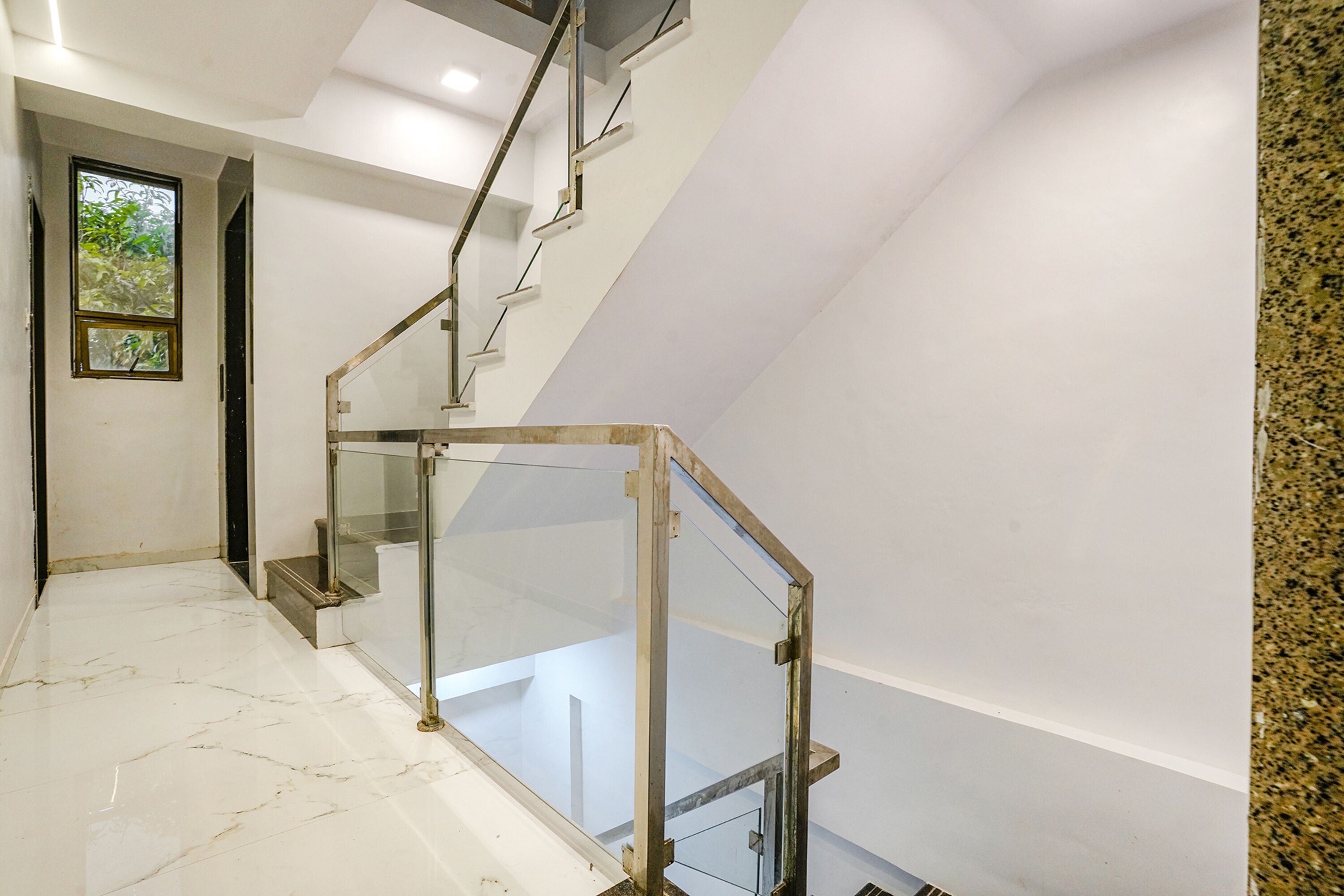 Eine moderne Treppe mit Glastrennwand und Marmorboden.