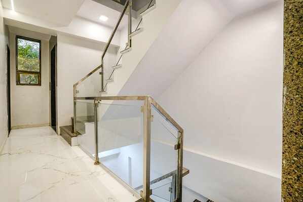 A modern staircase with glass railings and a marble floor. - Fabhotel Peralz (Mumbai)