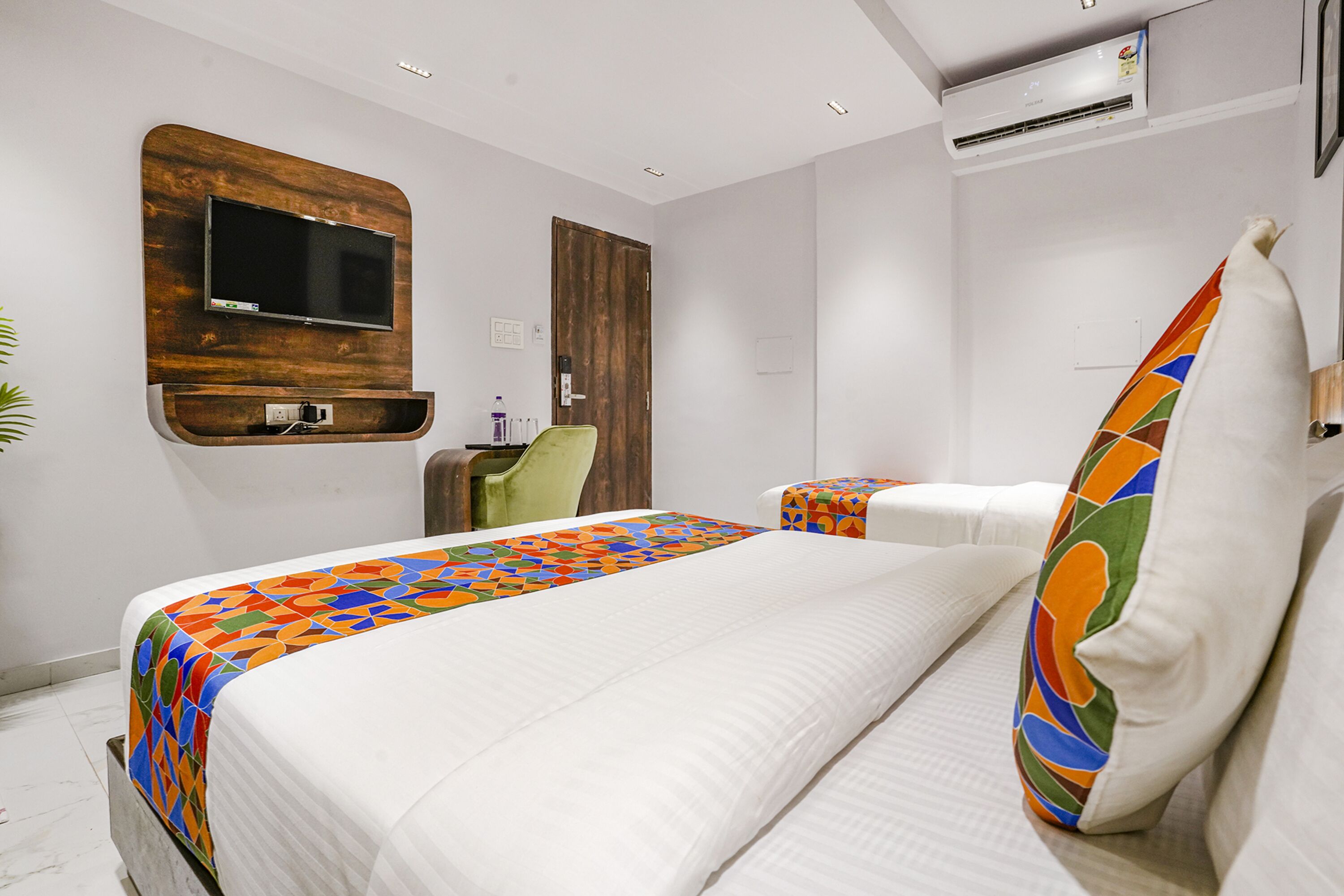 Ein Hotelzimmer mit einem großen Bett, einem an einer Holzplatte montierten Fernseher, einem Schreibtisch und einem Sessel.