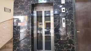 An elevator with a marble wall, a 'No Smoking' sign, and a 'G' sign above it. - Fabhotel Moon Light (New Delhi)