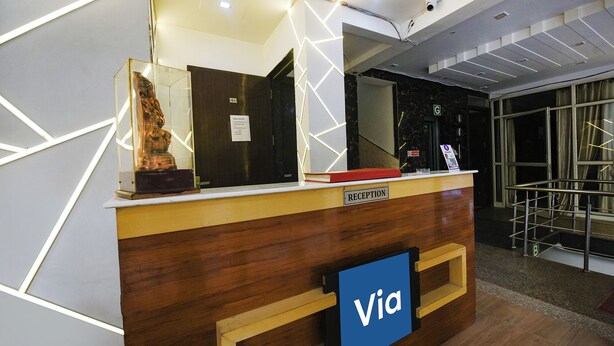 A reception desk with a 'Via' sign, a reception area with a marble wall, and a staircase leading to an upper level. - Fabhotel Moon Light (New Delhi)