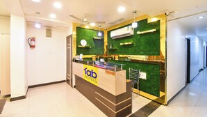 A reception desk with a green wall and a clock above it. - Fabhotel Raj Matrya Inn (Patna)