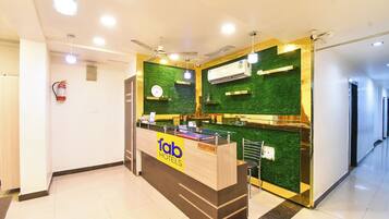 A reception desk with a green wall and a clock above it.