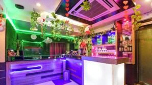 A bar area with a counter, shelves with bottles, and decorative plants. - Fabhotel Raj Matrya Inn (Patna)