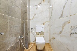 Et badeværelse med toilet, bruser og marmorvægge.