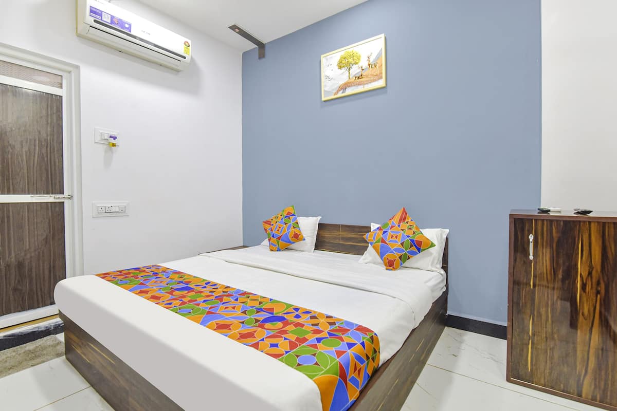 A neatly made bed with a colorful geometric-patterned bedspread, a wooden headboard, and two pillows with a multicolored geometric design.
