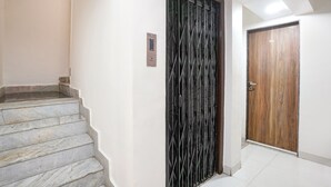 A staircase leading to a room with a wooden door and a metal gate. - Fabhotel Abhisiddhi Residency (Navi Mumbai)