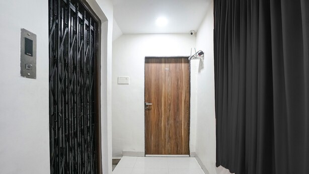 A hallway with a wooden door, a black metal gate, and a black curtain. - Fabhotel Abhisiddhi Residency (Navi Mumbai)
