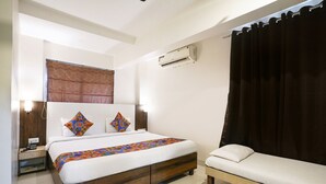 A hotel room with a bed, bedside table, and a small sofa. - Fabhotel Abhisiddhi Residency (Navi Mumbai)