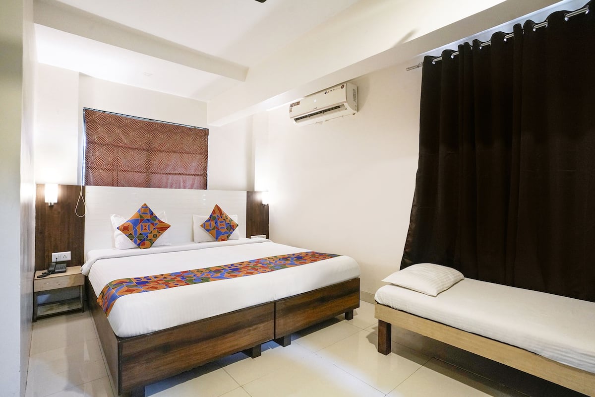 A hotel room with a bed, bedside table, and a small sofa.