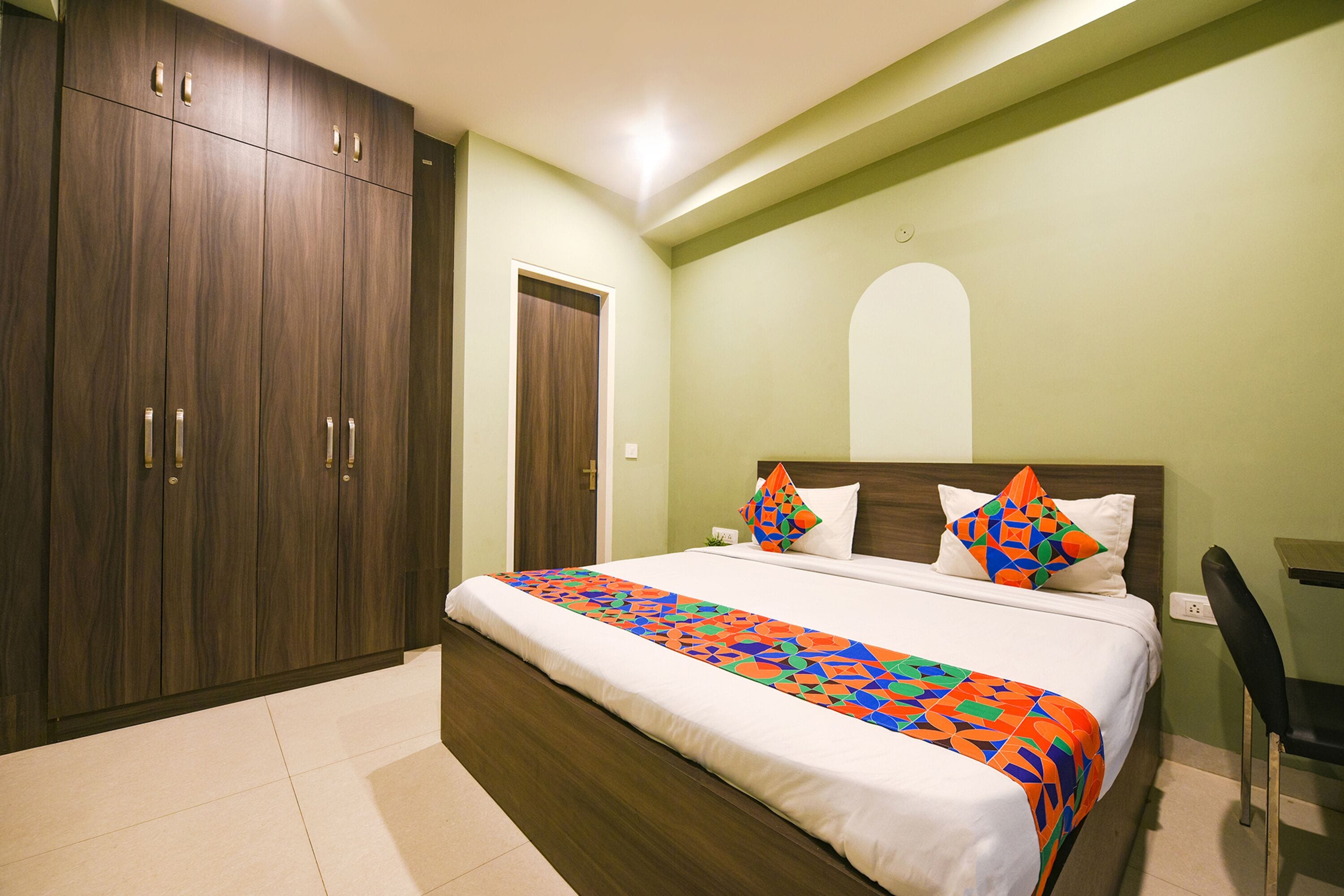 Een slaapkamer met een groot bed, een kledingkast, een bureau en een stoel.