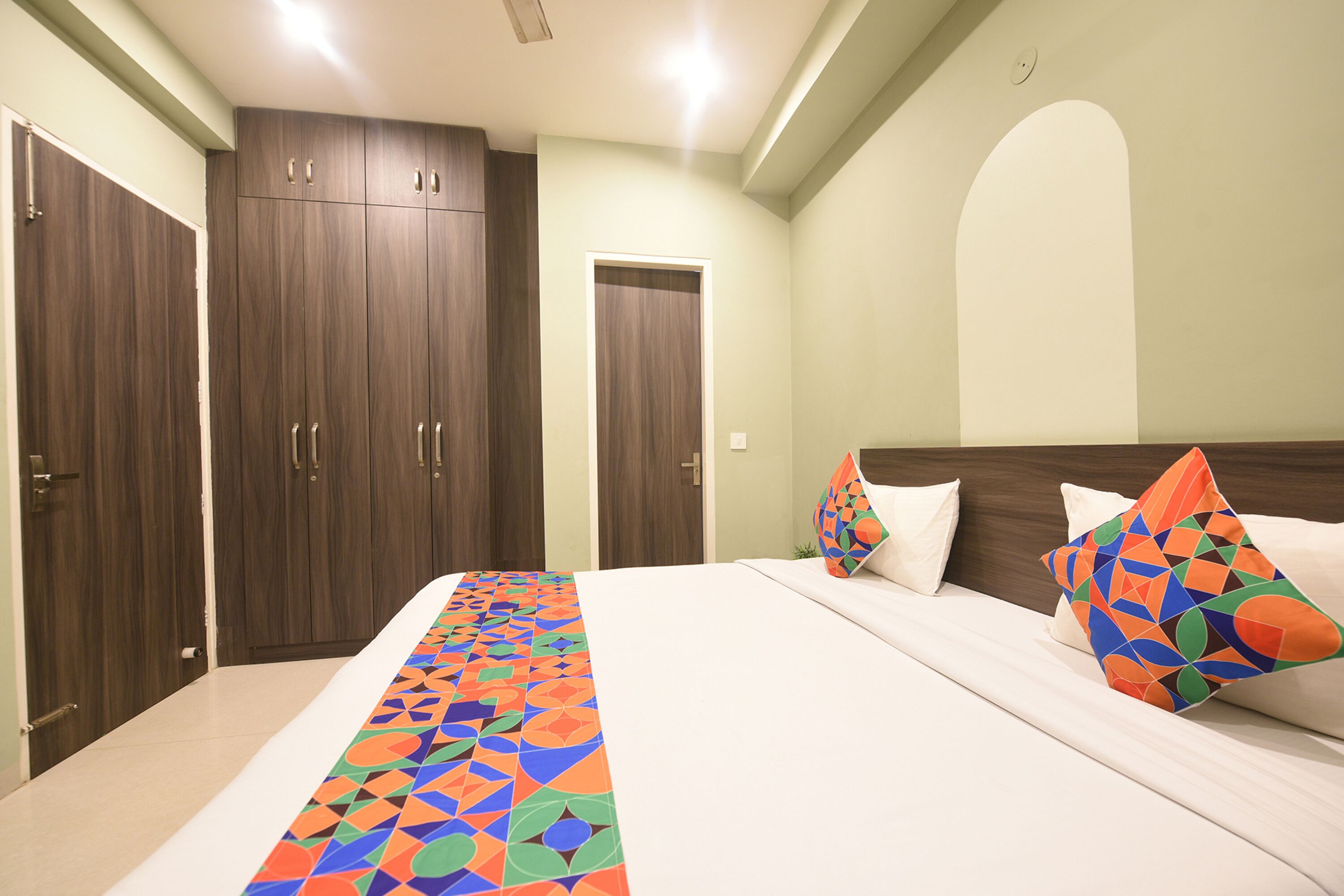 A bedroom with a large bed, two wardrobes, and a colorful bed runner.